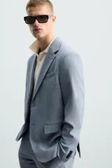 Blazer de corte slim fit confeccionada en tejido con lana, con cuello de solapas de muesca, cierre frontal de un botón, bolsillos laterales con solapa y bolsillo de vivo en el pecho.