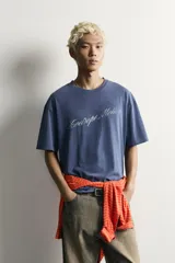 Remera boxy fit azul con efecto lavado, cuello redondo y manga corta, con estampa en el pecho.