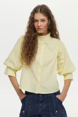 Camisa blanca de cuello mao con volados, mangas abullonadas y cierre frontal con botones.