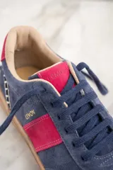 Zapatillas de gamuza azul con detalles en fucsia y suela marrón.