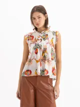 Blusa Pop de voile de seda y algodón, color blanco con estampado exclusivo de motivos frutales y florales. Presenta silueta en línea A, calce holgado, cuello alto fruncido con volados y escote profundo con volados caracol al frente.