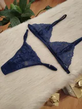 Conjunto de lencería de encaje en color azul profundo, compuesto por un corpiño triangular sin aro y una bombacha tipo colaless con detalles de encaje y transparencias.