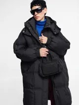 Campera puffer larga color blanco hueso, de corte amplio, con cierre frontal y capucha.