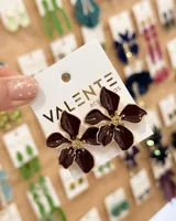 Caravanas con diseño de flor en tono bordó, con detalles dorados en el centro y borde.