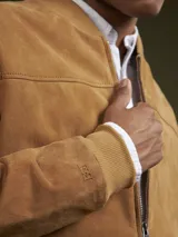 Campera bomber color camel de gamuza, con cierre frontal y bolsillos laterales.