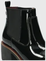 Botas Chelsea Hush Puppies de caña corta, confeccionadas en material sintético con acabado charol brillante. Presentan elásticos laterales para un calce sencillo, suela robusta de goma con plataforma y taco ancho.