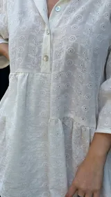 Vestido corto blanco con bordado calado, corte holgado, cuello camisero y mangas 3/4 con volados.
