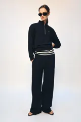 Pantalón tipo jogger de tiro medio con cintura elástica ajustable mediante cordones. Presenta un diseño de pierna recta, bolsillos laterales ocultos en las costuras y un detalle metálico con el logo ZA en la parte superior.