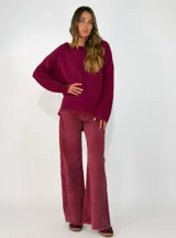 Sweater de punto gris con cuello redondo, mangas largas y diseño asimétrico, siendo más corto en la parte delantera y más largo en la trasera, con detalles de terminación en contraste.