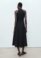 Vestido midi negro sin mangas, con cuello en V, cierre frontal con botones y cinturón ajustable del mismo tejido. Diseño evasé con mezcla de lyocell y lino.
