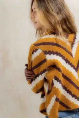 Sweater de punto jacquard con diseño de chevron en tonos celeste y marrón. Presenta cuello redondo, corte holgado y mangas largas con hombros abullonados.