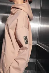 Buzo oversize color nude confeccionado en frisa, con capucha amplia, bolsillo canguro, terminaciones de puño y ruedo con rib, y logo de la marca bordado en el centro delantero.