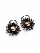 Aros tipo argolla de metal plateado con dijes colgantes de acrílico espejado en forma de sol o estrella, en tonos marrón y transparente.