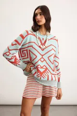 Buzo oversize de punto color marfil con diseño geométrico jacquard en tonos rosado, amarillo, celeste y marrón. Cuenta con cuello redondo y mangas largas.