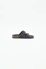 Sandalia baja abierta de estilo 'slide' con dos tiras ajustables con hebillas metálicas. Las tiras están completamente decoradas con bordados de mostacillas, canutillos y strass en tonos negros y grises. La plantilla es de corcho visible forrada en cuero negro, y la suela es de goma.