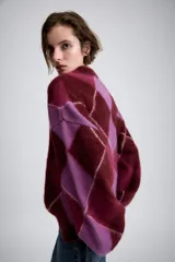 Jersey de punto de lana con diseño de rombos en tonos bordó y lila. Presenta cuello redondo, manga larga con puños ajustados y corte holgado.