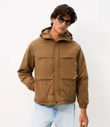 Campera utilitaria de poliéster color tostado, con capucha ajustable, cuello alto, cierre frontal con cremallera y solapa con botones a presión, y bolsillos frontales grandes con solapa.