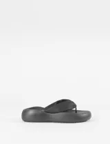 Sandalia tipo ojota con plataforma, confeccionada en cuero sintético y base de caucho. Presenta una tira ancha acolchada en el empeine y diseño ergonómico.