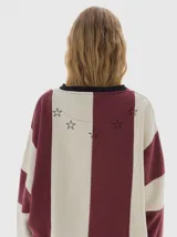 Buzo de friza con cortes verticales en color bordó y beige, calce oversized, manga larga, hombros caídos y cuello a la base.