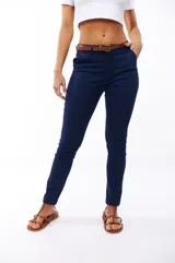 Pantalón azul marino de corte skinny, con bolsillos laterales y traseros. Se ajusta a la cintura con cinturón de cuero marrón.