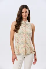 Camisa sin mangas de lino y algodón, con estampado floral en tonos violeta y verde sobre base beige, cuello camisero y cierre frontal de botones.