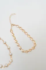 Set de cuatro brazaletes dorados con diferentes diseños: uno de eslabones tipo concha, uno con perlas engarzadas, uno de cadena fina y uno con eslabones en forma de espiga.
