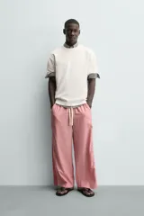 Camiseta blanca de corte relajado (relaxed fit) con cuello redondo y manga corta. Presenta un estampado grande en la espalda que simula dados rojos con letras y corazones.