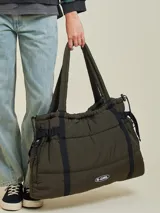 Bolso tipo tote bag de diseño acolchado en color negro, con correas ajustables y cierre lateral. Presenta el logo de la marca Rusty en la parte frontal.