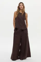 Pantalón marrón de lino, con pernera ancha, pinzas en el frente y bolsillos laterales.
