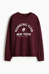 Buzo de tejido de punto color bordó, con cuello redondo y puños y bajo acanalados. Presenta un estampado frontal en blanco con el texto "RUNNING CLUB NEW YORK Central Park - Manhattan".