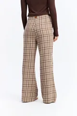 Pantalón de tiro medio con corte recto y leve apertura en el bajo. Presenta un diseño de estampado a cuadros en tonos beige y marrón.