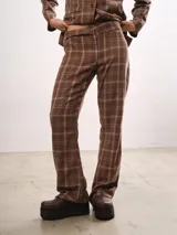 Pantalón de corte recto con estampado a cuadros en tonos marrones. Presenta cierre frontal con botón y bolsillos laterales.