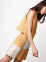 Short de lino color beige y naranja, de tiro alto con elástico en la pretina trasera, cierre delantero y botón, bolsillos delanteros y dobladillo invisible.