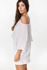 Blusa de lino italiano color blanco, con diseño holgado, escote asimétrico estilo off-shoulder y mangas cortas amplias.