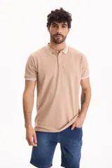 Remera polo de piqué color beige, de manga corta, con cuello y puños acanalados adornados con líneas blancas finas. Cuenta con tapeta de dos botones.