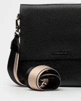 Bandolera color beige con correa ancha de tela negra con el nombre de la marca en blanco.