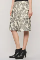 Bermuda de gabardina de calce relajado, tiro largo, con estampado estilo paisley en tonos beige y negro, y bolsillos delanteros estilo cargo con broches metálicos.