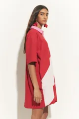 Túnica de algodón con diseño bicolor en bloques diagonales rojos y blanco off-white, con cuello camisero, botonera central y mangas cortas en contraste de color rosado.