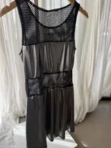 Vestido corto sin mangas en combinación de tejido de red negro y tela lamé plateada con efecto metalizado, con paneles transparentes y diseño acampanado.