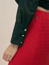 Falda larga color crema, tejida en algodón, con cintura elastizada y detalle de cobre con logo.