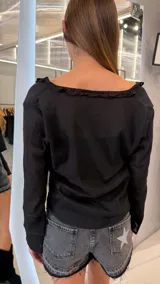 Top negro de manga larga con escote en V, detalles de volados en el cuello y cordones ajustables en el frente.