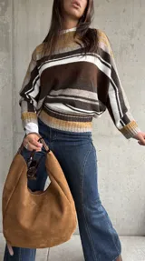 Sweater de punto con diseño de rayas horizontales en tonos chocolate, mostaza, blanco y gris. Presenta cuello redondo, mangas largas y corte holgado.