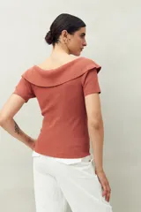 Top blanco tejido en punto acanalado con cuello amplio que se abre hacia los hombros y mangas cortas. Ajustado al cuerpo.