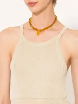 Vestido largo color beige, tejido en hilo fino con sutil brillo metálico. Diseño ajustado al cuerpo y con transparencia.