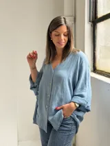 Camisa oversize de lino color celeste, con escote en V, cierre frontal con botones y mangas largas holgadas.