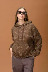 Buzo con capucha de calce relajado, con estampado animal print tipo piel de serpiente en tonos marrones. Presenta bolsillo frontal tipo canguro y cordones ajustables en contraste.