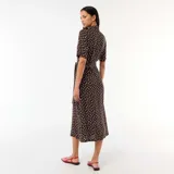 Vestido midi marrón con estampado de lunares blancos, estilo camisero con cuello solapa, mangas cortas, cierre frontal de botones y cinturón para anudar en la cintura.