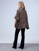 Poncho de tejido soft, marca Weatherproof, con diseño a cuadros en tonos azul marino, beige y celeste. Posee cuello alto con cierre metálico y bolsillos delanteros.