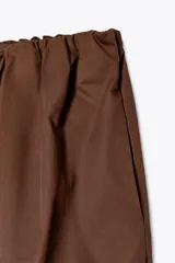 Pantalón negro de tiro medio, estilo culotte, con cintura elástica fruncida y piernas muy anchas. Posee bolsillos laterales ocultos.