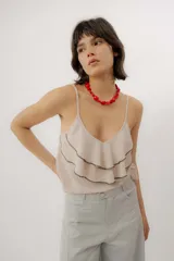Musculosa color beige de tirantes finos regulables, con escote en V y volados superpuestos decorados con costuras en contraste.